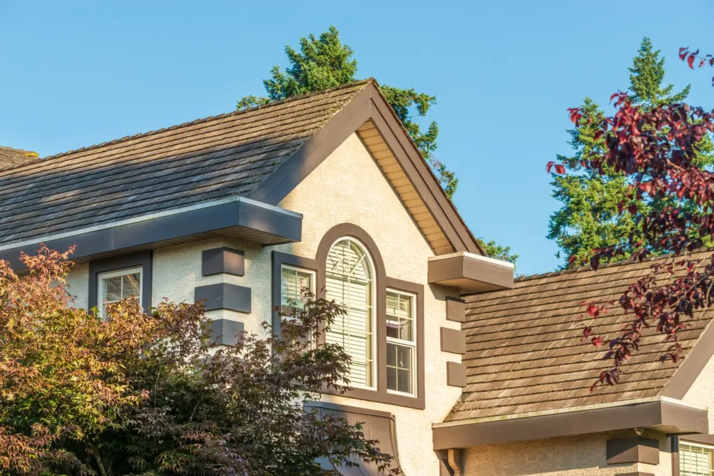 Exterior of a home with a brown roof and stucco walls, showcasing architectural details.