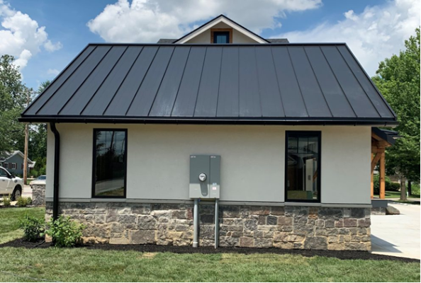 Modern building with a dark metal roof, stone base, and black-framed windows.